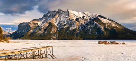 Téléchargez les photos : Vue panoramique du magnifique lac Minnewanka gelé avec des montagnes rocheuses en hiver le soir au parc national Banff, Alberta, Canada - en image libre de droit