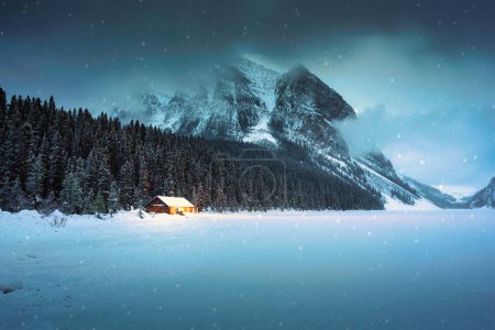 Foto de Hermoso paisaje del lago Louise con cabaña de madera brillante y montañas rocosas con nieve cubierta en invierno en el parque nacional Banff, Alberta, Canadá - Imagen libre de derechos