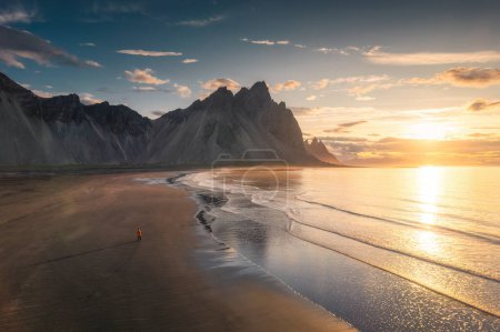 Photo for Breathtaking view of Vestrahorn mountain during sunrise and man standing alone on black sand beach in Stokksnes headland peninsula on summer at Iceland - Royalty Free Image