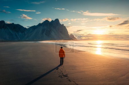 Photo for Breathtaking view of Vestrahorn mountain during sunrise and man standing on black sand beach in Stokksnes headland peninsula on summer at Iceland - Royalty Free Image