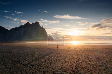 Photo for Breathtaking view of Vestrahorn mountain during sunrise and man standing alone on black sand beach in Stokksnes headland peninsula on summer at Iceland - Royalty Free Image