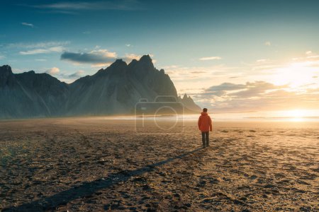 Photo for Beautiful view of sunrise over Vestrahorn mountain with a tourist man walking on black sand beach in summer at Stokksnes peninsula, Iceland - Royalty Free Image