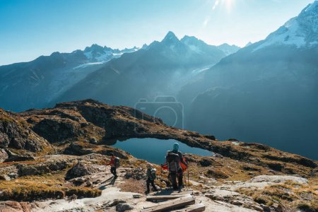 Téléchargez les photos : Paysage alpin français d'un groupe de randonneurs escaladant le lac des Cheserys avec le massif du Mont Blanc en automne par temps ensoleillé en Haute Savoie, France - en image libre de droit