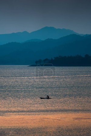 Foto de Colorida vista al atardecer del embalse Kaeng Krachan con barco pesquero y canoa de remos turística en Phetchaburi, Tailandia - Imagen libre de derechos
