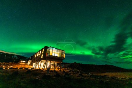 Beautiful scenic view of Aurora borealis, Northern lights glowing over luxury hotel on mount Hengill in winter at Nesjavellir, Iceland