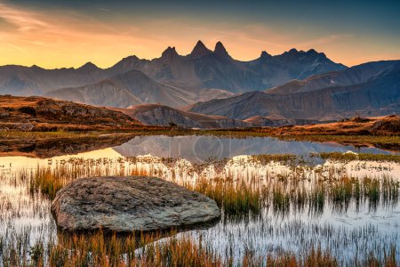 Picturesque landscape of sunrise shines over Lac Guichard with Arves massif and lake reflection in autumn at Aiguilles d Arves, French Alps, Savoie, France
