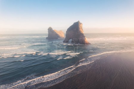 Téléchargez les photos : Aerial view of Picturesque sunrise shining over Wharariki beach and archway islands on Tasman sea at West of cape farewell, New Zealand - en image libre de droit