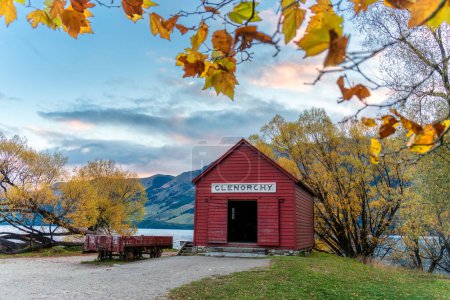 Wooden red building of boat shed Glenorchy in autumn forest by Lake Wakatipu in the evening at Queenstown, Otago, New Zealand