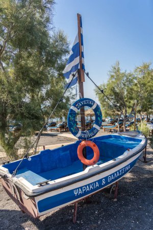 Foto de Perivolos Beach, Santorini, Grecia - agosto de 2022: barco pescador de madera azul en desuso utilizado para anunciar la taberna local en una popular playa de Santorini - Imagen libre de derechos