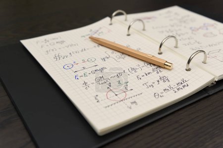 Téléchargez les photos : Un cahier rempli d'équations physiques complexes et d'annotations colorées suggère une plongée profonde dans l'étude académique, avec un crayon indiquant un travail en cours. - en image libre de droit