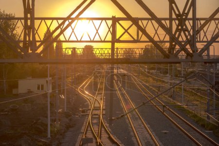 Coucher de soleil coloré sur les voies ferrées d'Ostrowiec.Structures métalliques et voies ferrées immergées dans les rayons dorés du soleil couchant un soir de mai. Voies ferrées au crépuscule.