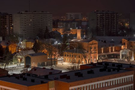  La ville la nuit. Vue des bâtiments historiques (et modernes) éclairés de la ville. La ville (Ostrowiec Swietokrzyski) par une nuit d'automne avec de la neige fraîchement tombée. Le bâtiment historique magnifiquement restauré de la brasserie est clairement visible et lumineux. 