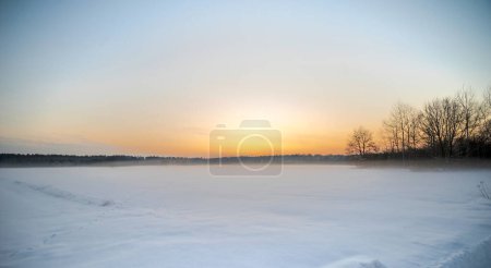  Eine schneebedeckte Waldlichtung kurz nach Sonnenuntergang an einem Dezemberabend. Die Schönheit der Natur in den polnischen Wäldern der Region Swietokrzyskie an einem verschneiten, aber immer noch herbstlichen Nachmittag. Spuren von Waldtieren im Schnee sichtbar.