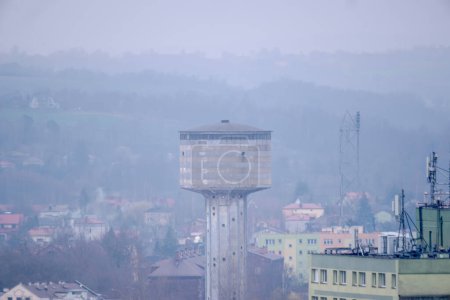 Un plan haut d'une tour. Le vieux château d'eau caractéristique dans les locaux de l'ancienne aciérie d'Ostrowiec par un après-midi de mars brumeux. Vue sur la ville (sa partie historique) par une journée brumeuse à l'aube du printemps .  