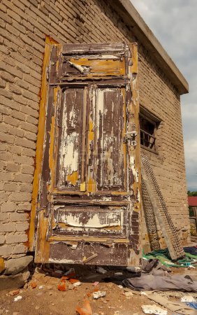 Old abandoned house in the city.Old brick building - door with peeling paint, renovation. A historic white brick building with old peeling paint doors being renovated and restored. There is a cloudy sky overhead .  