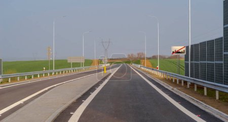 The highway in the city of the poland.The road leading out of the city - a sign indicating the end of the built-up area. A road (ring road) leaving the city on the afternoon of a spring day.Visible noise protection screens .  