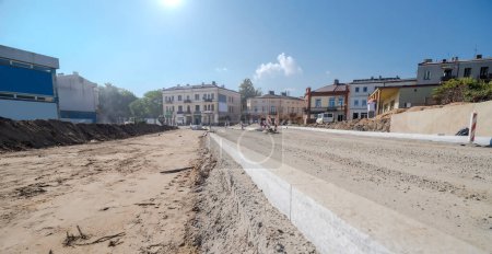 A view of the road in the city of the new town. Road construction in Ostrowiec under a blue sky at midday in September. Granite curbs of a road under construction in the city. Construction chaos in the city center.  