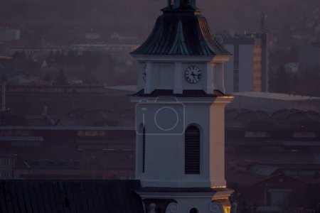 Blick auf die Stadt Ostrowiec in Polen. Kirchturm mit Uhr. Sichtbare Industriehallen - ein altes Stahlwerk - liegen über der Stadt. Ostrowiec Swietokrzyski - der historische Teil der Stadt, der nach Sonnenuntergang sichtbar ist.  
