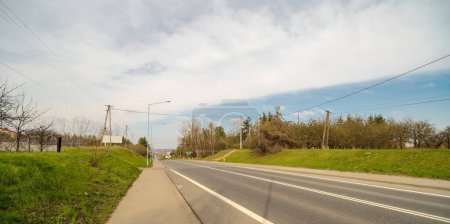 Route asphaltée vide dans la campagne au printemps.Route au printemps à la périphérie d'Ostrowiec sous un ciel nuageux. Ciel bleu printanier, avec un lourd voile de nuages, sur la route entrant dans la ville .  