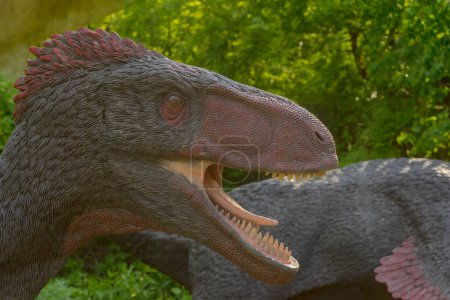 Photo for Dinosaur model on the grass. Poland Batow May 30, 2023 at 16:08. Utahraptor (with friends) on the hunt. A group of some of the largest known dromaeosaurs on the hunt. Feathered and intelligent theropods among the vivid green trees in spring. - Royalty Free Image