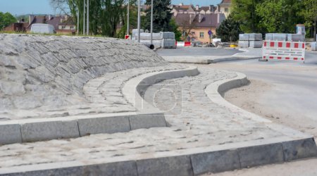 Straßenbaustelle - eine Insel mitten im Kreisverkehr aus Granit. Rekonstruktion der Verkehrswege in der Stadt - ein neuer Kreisverkehr mit einer Insel aus Granitpflastersteinen und Bordsteinen aus demselben Material.   