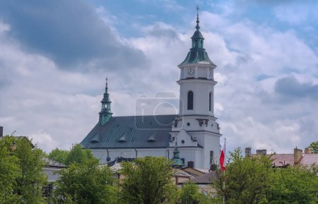 Belle vue sur la vieille église de la ville de la Pologne. La collégiale historique de Saint Michel l'Archange sur fond de ciel nuageux pittoresque. Le jour du printemps. Vue de la place principale Le drapeau polonais flotte sur le mât.  