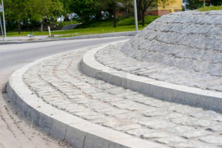 Stone pavement in the city.  An island on a newly built roundabout - made of granite paving stones and curbs. Reconstruction of the urban road system in the city - construction of a large turbine roundabout. 