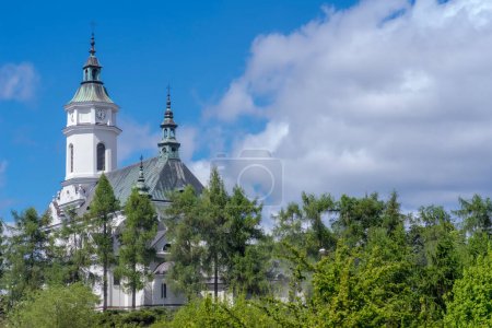 The old church . The historic church (collegiate church) of Saint Michael the Archangel on a sunny spring day. A several hundred years old Catholic temple among spring greenery on a hill under a blue sky in Ostrowiec.  