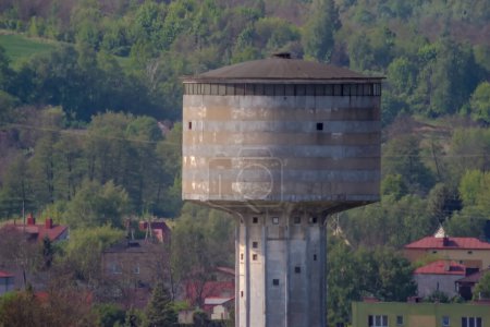 La tour au sommet d'une colline. Tour d'eau historique en béton par un matin de mai. Un point de repère caractéristique dans la vieille ville métallurgique (Ostrowiec) un matin de printemps sur fond de collines boisées . 