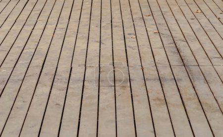 Wooden floor background. wooden texture.Wooden floor of a music stage, terrace with sand and leaves on top. Floorboards laid with quite large gaps - the floor of a music stage in a concert hall in a city park.  