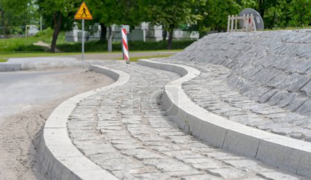 Die Insel des im Bau befindlichen Kreisverkehrs besteht aus Granit. Die Mitte des Kreisverkehrs besteht aus Granitpflastersteinen und ähnlichen Bordsteinen. Straßenbaustelle in der Stadt.  
