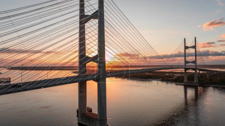 Die Dames Point Bridge in Jacksonville, Florida, bei Sonnenuntergang mit dem Himmel und der Brücke, die sich auf dem Fluss spiegelt.