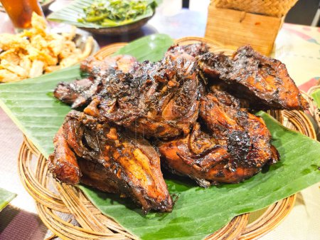 grilled chicken on a earthen plate with banana leaves, traditional Indonesian food concept