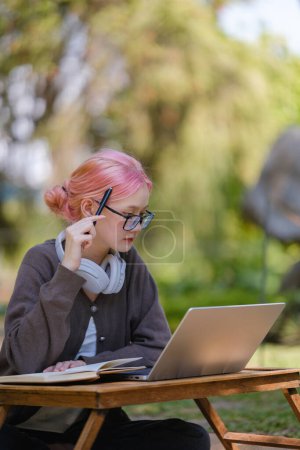 Young gorgeous woman with pretty face thinking about something while sitting with laptop computer in the garden. High Quality.