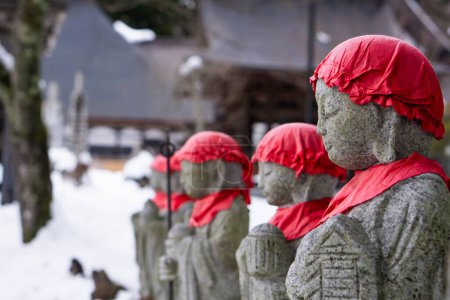 Japanische Izostatuen mit roten Kappen in einer Winterlandschaft. Fotografiert in den japanischen Alpen.