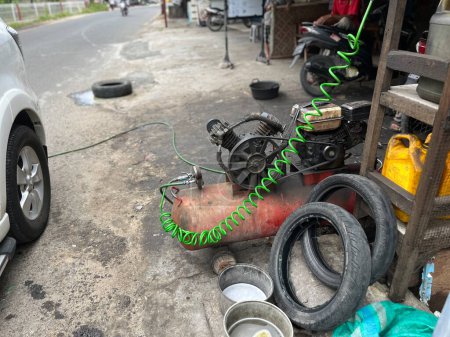 Car repair shop, air pump machine compressor, pile of used oil bottles and used tires