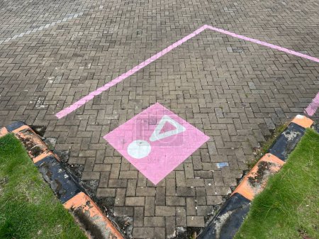Pflastersteinparken mit einzigartigen rosafarbenen Parklinien und Symbol auf Rastplätzen