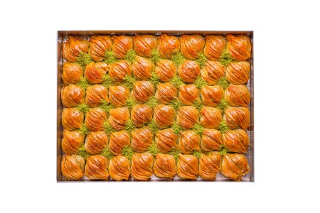 Téléchargez les photos : Un plateau de bonbons de baklava au midye turc, décoré de pistaches, isolé sur un fond blanc - en image libre de droit