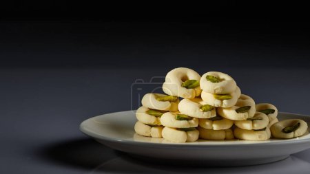 Foto de Un plato de dulces árabes con pistachos representados sobre fondo blanco y fondo gris y negro - Imagen libre de derechos