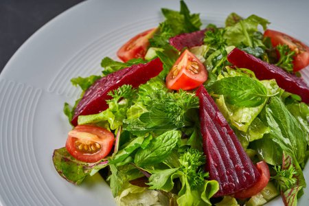 Foto de Una foto de cerca de un plato de ensalada que contiene lechuga, tomate, remolacha roja y menta - Imagen libre de derechos