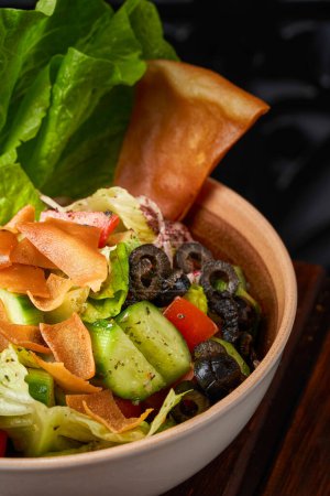 Photo for A close-up of a plate of Syrian fattoush salad with olives and toasted bread - Royalty Free Image