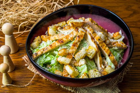 Téléchargez les photos : Assiette de salade César au poulet sur un plancher de bois - en image libre de droit