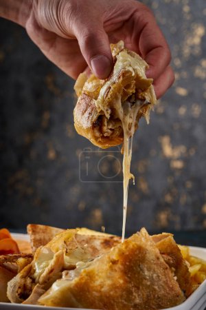 Photo for A person holds a piece of shawarma and melted cheese comes out of it - Royalty Free Image