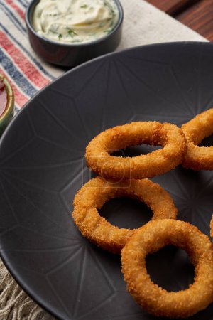 Foto de Primer plano de los anillos de cebolla frita en un plato negro - Imagen libre de derechos