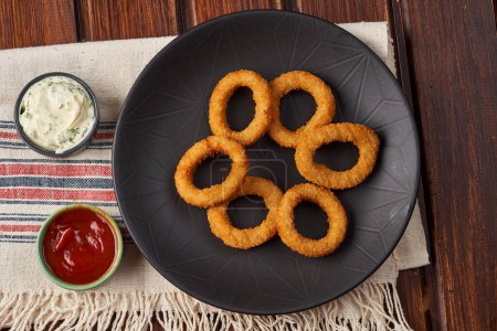 Téléchargez les photos : Gros plan des rondelles d'oignon frites dans une assiette noire - en image libre de droit