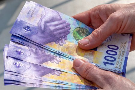 Téléchargez les photos : Mains tenant une pile de francs suisses argent - en image libre de droit