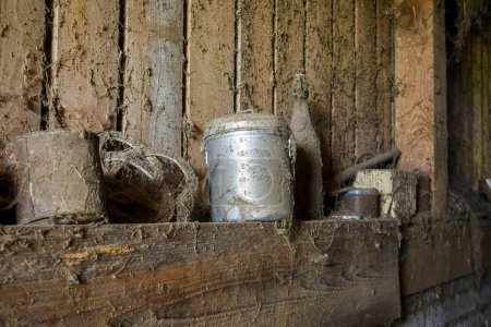 Téléchargez les photos : Cruche à lait vintage en métal avec toiles d'araignée et poussière autour, stockée dans une ancienne grange avec des bouteilles et des articles de la ferme - en image libre de droit