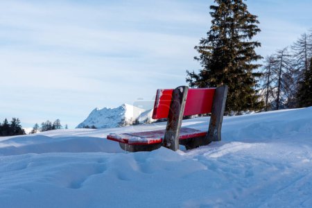 Téléchargez les photos : Banc rouge recouvert de neige sur les Alpes suisses - en image libre de droit