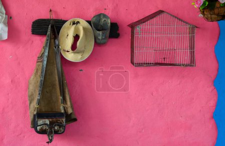 Alter ländlicher Kleiderbügel mit Vogelkäfig, Hut, altem Steigbügel und Lederwaren in Kolumbien