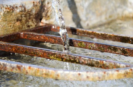 Photo for Old rusty iron bars in a fountain in the alps - Royalty Free Image